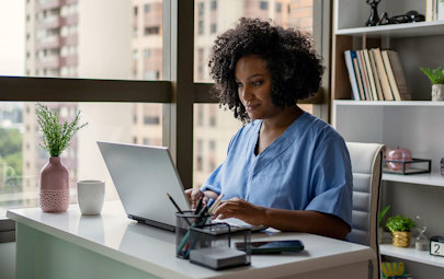 Physician working on a laptop entering in patient information Physician working on a laptop entering in patient information