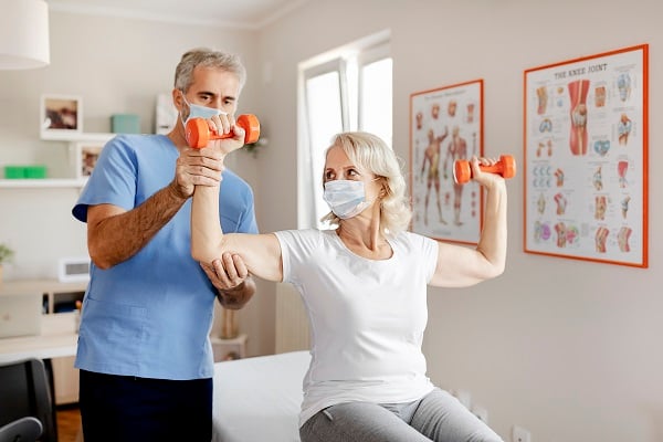 Physical Therapist Helps Woman Lift Weights