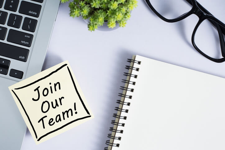 Join Our Team sticky note with notepad, laptop and glasses near