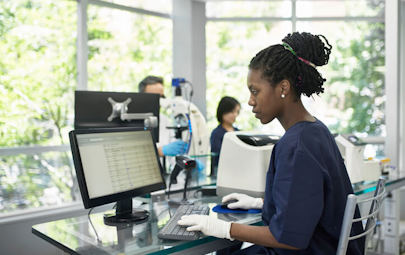 Medical technician working on computer in lab Medical technician working on computer in lab