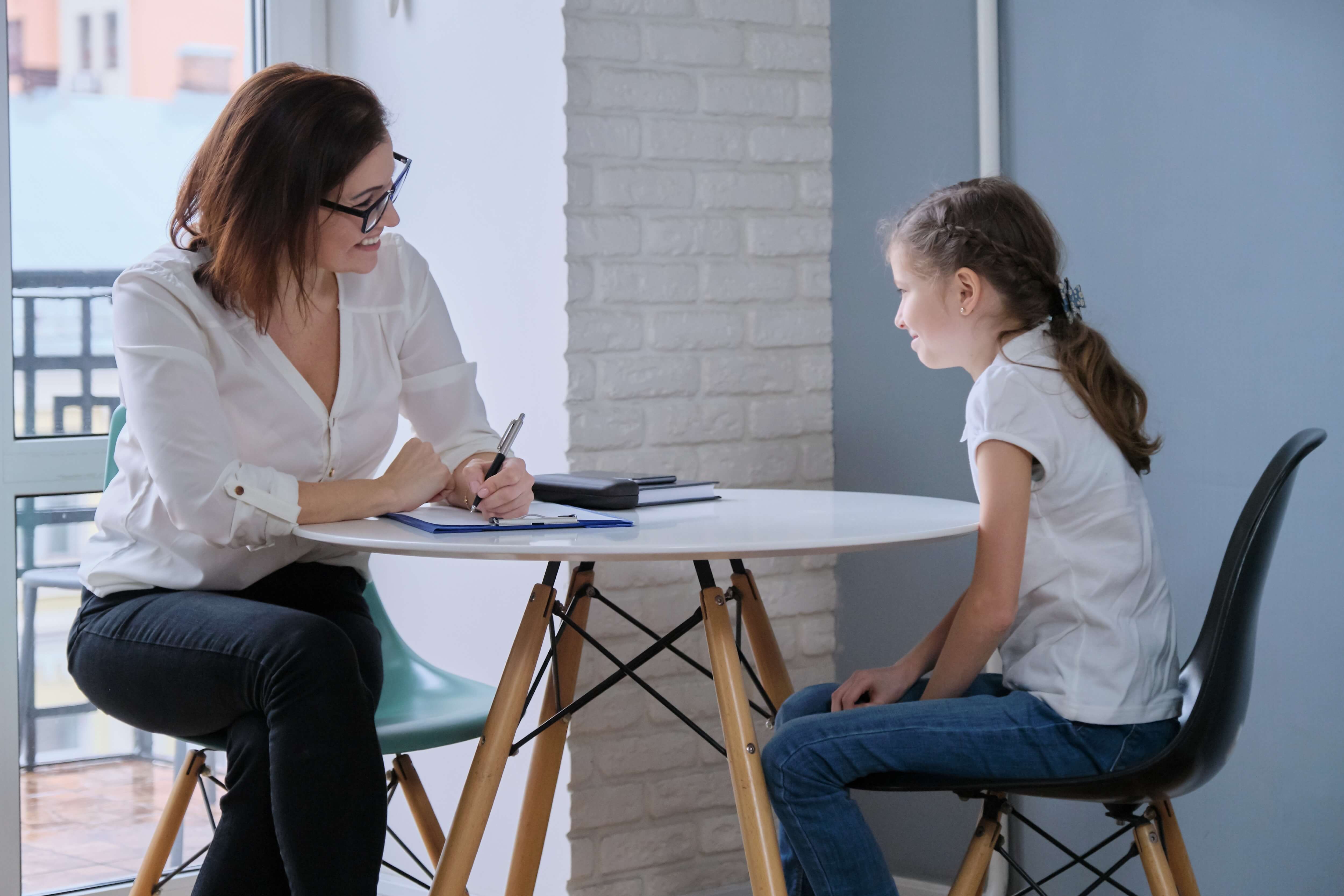 School Psych and child talking at round table.