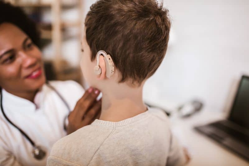 Smiling deaf boy with ear implant at doctor's office