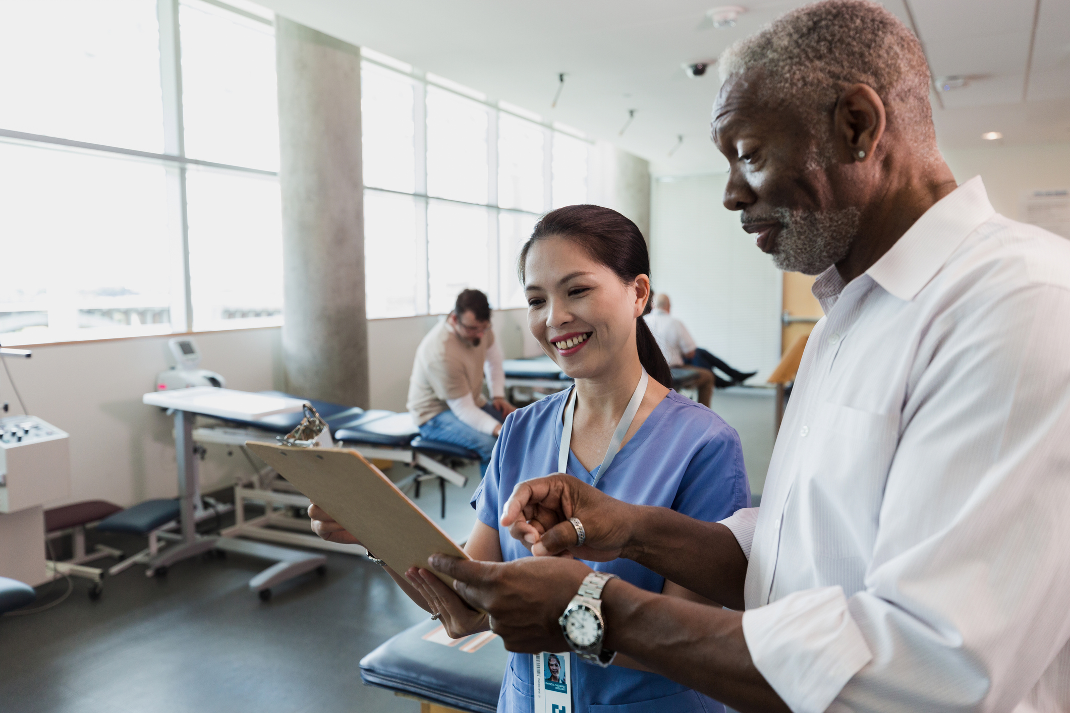 black male and Hispanic nurse talk inside clinic black male and Hispanic nurse talk inside clinic
