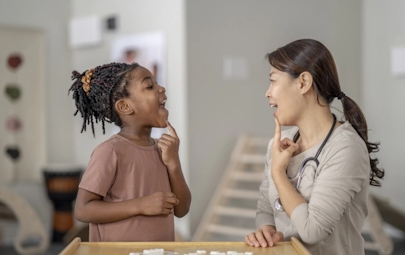 Therapist guiding young patient through speech therapy Therapist guiding young patient through speech therapy