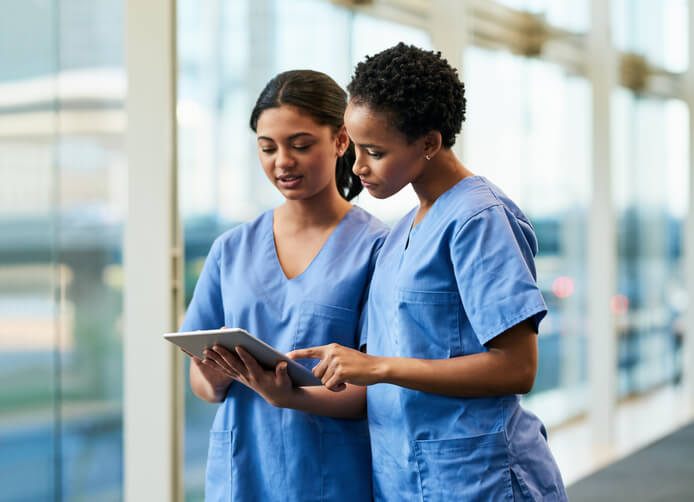 two healthcare professionals looking over a tablet while in hospital