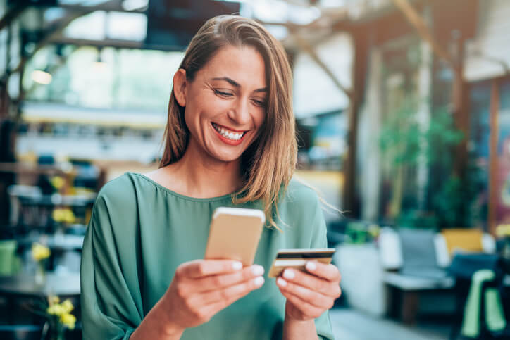 smiling woman entering her credit card for mobile phone purchase