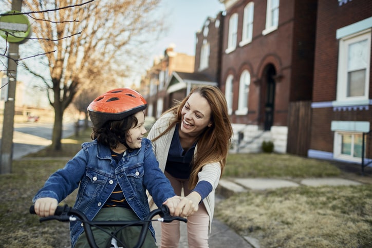 Happy mom guiding child as he rides his bike Happy mom guiding child as he rides his bike