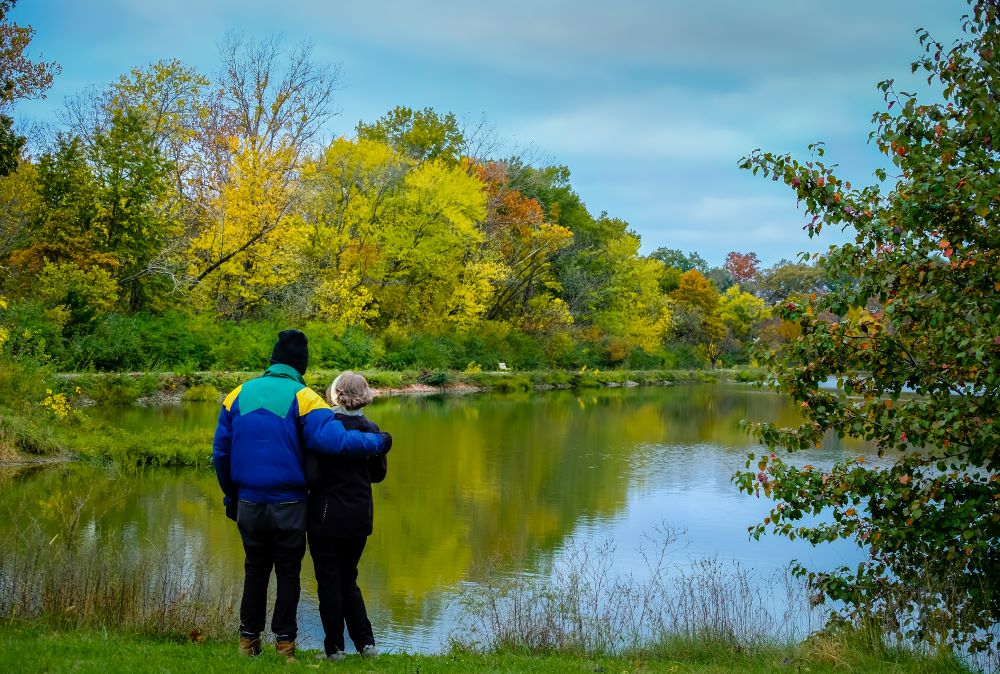 Couple hugging standing near a lake in a wooded area. Couple hugging standing near a lake in a wooded area.