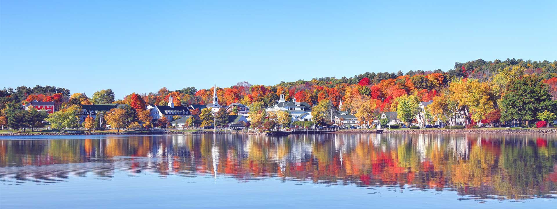 Lake in New Hampshire that is dotted with houses and autumn colored trees