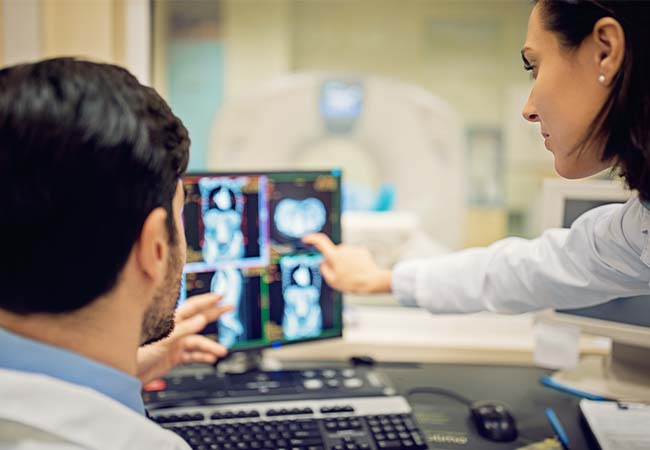 Two physicians pointing at x-rays on computer